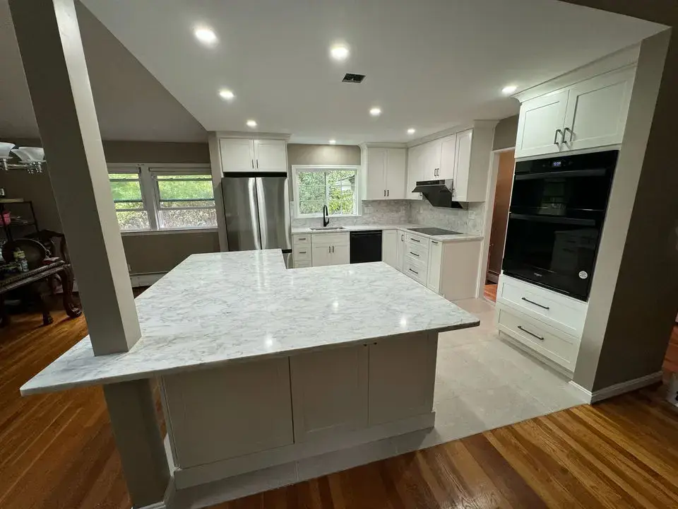 Modern white and gray kitchen remodel featuring quartz countertops and center island with seating.