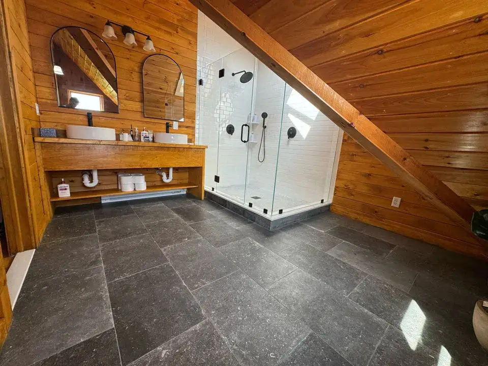 Rustic-style bathroom featuring pine wood paneled walls, a double vessel sink vanity, and glass walk-in shower.